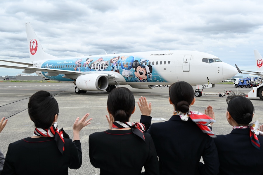 JAL staff handing out commemorative stickers to passengers